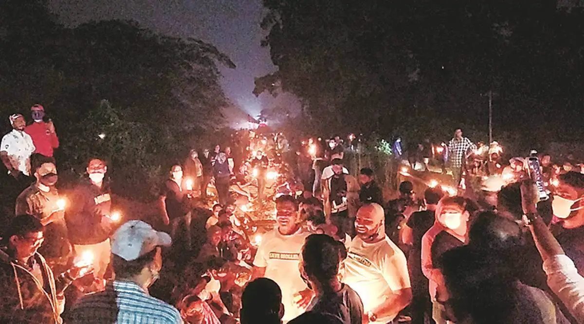 A large crowd with candles standing on the railway line at night