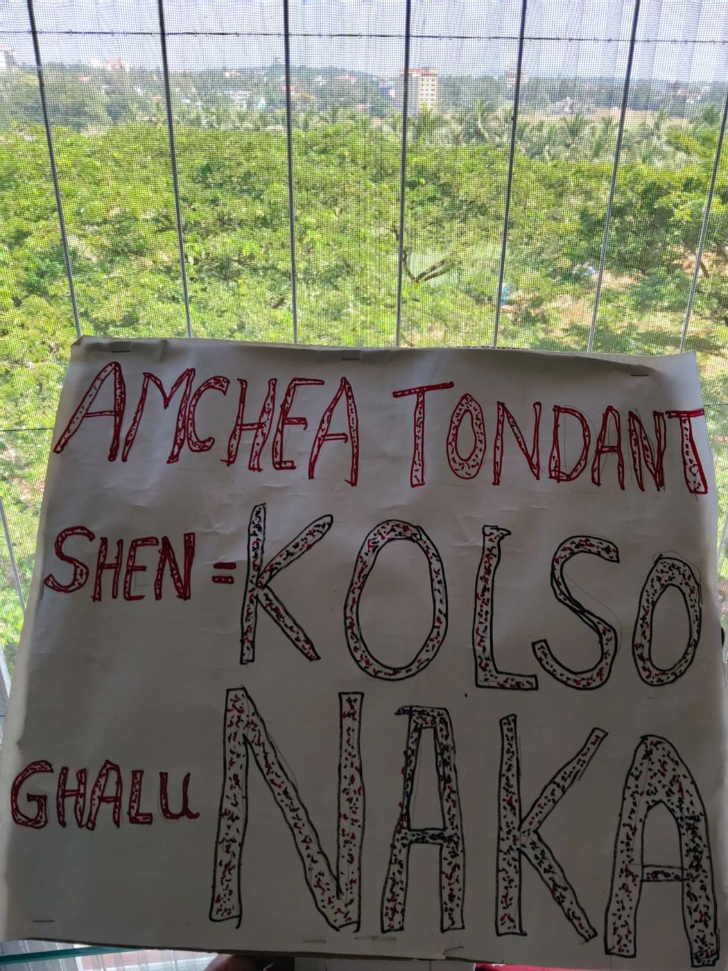 Hand-painted placard reading 'Amchea tondant shen — Kolso Naka'